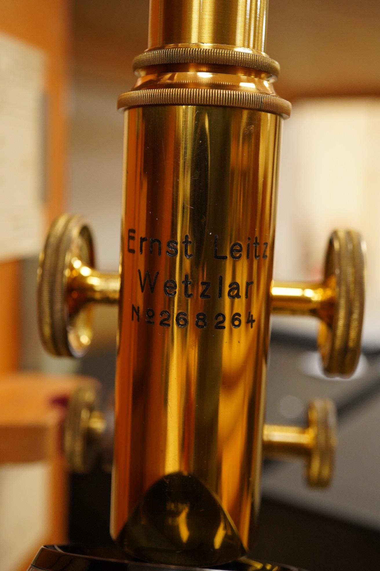 An early 20th century teak cased Ernst Leitz, Wetzlar brass and cast iron monocular microscope, serial no. 268264, with fitted interior to the case and card box of specimen slides, case dimensions; 36cm high, 19cm wide,